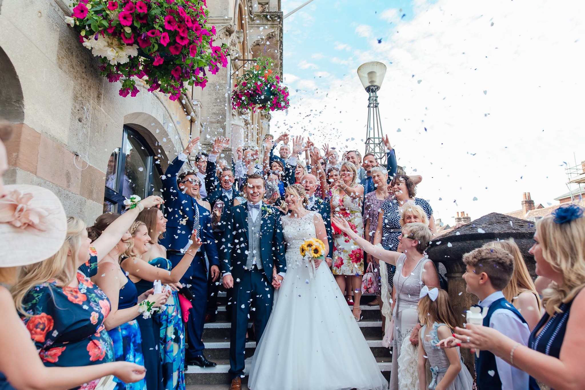 A couple walking down the Guildhall steps while guests throw confetti
